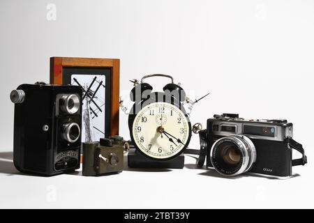 Collezione di fotocamere vintage con orologio analogico e foto artistiche su sfondo bianco Foto Stock
