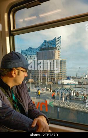 Passeggeri sulla linea U3 della metropolitana di Amburgo, che guardano fuori dalla finestra della sala concerti Elbphilharmonie Foto Stock