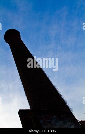 Il passato industriale incontra la natura - vista Skyward di Chimney Red Brick invecchiato Foto Stock