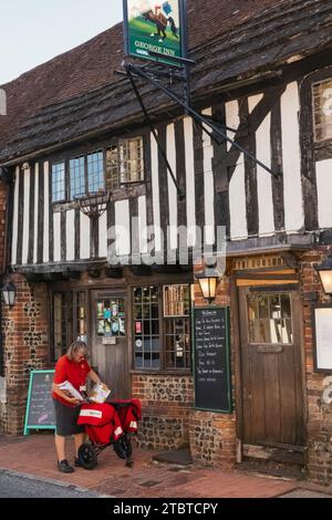 Inghilterra, East Sussex, Alfriston, Alfriston Village, Street Scene with Female Postal Worker Delivering mail Foto Stock