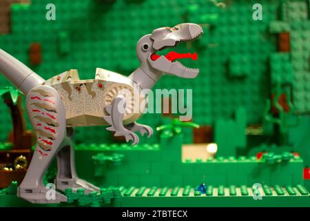 Primo piano del giocattolo dei dinosauri in mattoni con interblocco sullo sfondo del blocco verde Foto Stock