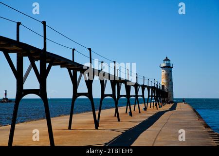 Molo industriale che conduce al faro bianco sotto il cielo azzurro del Michigan Foto Stock