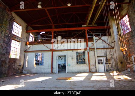 Decadimento soleggiato all'interno del magazzino industriale abbandonato Foto Stock