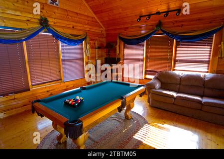 Accogliente cabina rustica interna con tavolo da biliardo e divano in pelle nel Tennessee Foto Stock