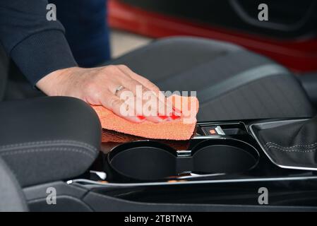 Mano da donna con panno in microfibra per la pulizia della console dell'auto Foto Stock