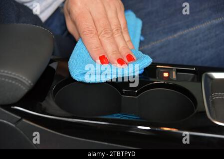 Mano da donna con panno in microfibra per la pulizia della console dell'auto Foto Stock