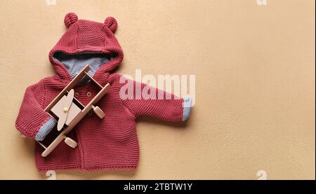 Elegante pullover per bambini e giocattolo aereo su sfondo beige con spazio per il testo Foto Stock