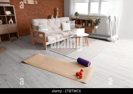 Tappetino fitness con manubri e rullo in schiuma all'interno del soggiorno Foto Stock