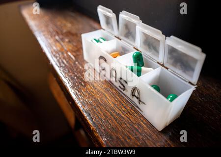 scatola organizer per pillole, con pillole arancioni e verdi Foto Stock