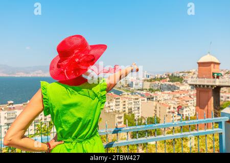 Donna turistica che guarda lo skyline di Smirne dalla terrazza del punto di riferimento storico di Asansor in Turchia, abbellisce il paesaggio urbano di Smirne con la sua eleganza senza tempo. Foto Stock