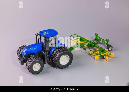 Vista ravvicinata della prospettiva autonoma del modello di trattore agricolo miniaturizzato radiocomandato dotato di aratro. Foto Stock