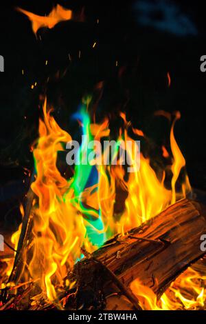 Vibrante spettro di fiamme nel fuoco a legna di notte con riflessi blu-verdi Foto Stock
