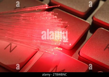 Trefoli in fibra ottica che trasmettono luce rossa sulla tastiera del computer, vista macro Foto Stock
