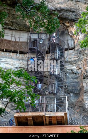 I visitatori della fortezza di Sigiriya Rock in Sri Lanka salgono la scala a chiocciola che conduce dal muro dello specchio alla grotta degli affreschi. Foto Stock