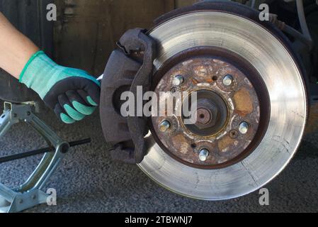 Servizio di sostituzione delle pastiglie dei freni a disco per auto con la mano del meccanico, rotore dei dischi dei freni senza ruote Foto Stock