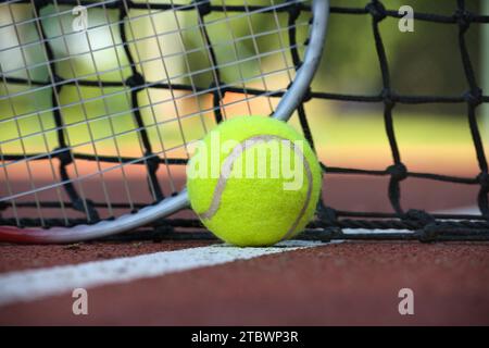 Scena tennis con rete nera, palla su linea bianca e racquet in basso angolo di visione e fuoco selettivo Foto Stock