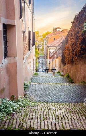 Stradina stretta di Roma con i turisti al tramonto in estate Foto Stock