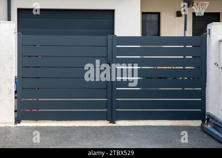 moderno cancello grande grigio in acciaio a doppia porta, portale in alluminio con lame e sobborghi Foto Stock