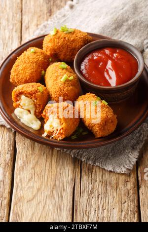 Palline di riso fritte ripiene di mozzarella suppli al telefono primo piano sul piatto sul tavolo. Verticale Foto Stock