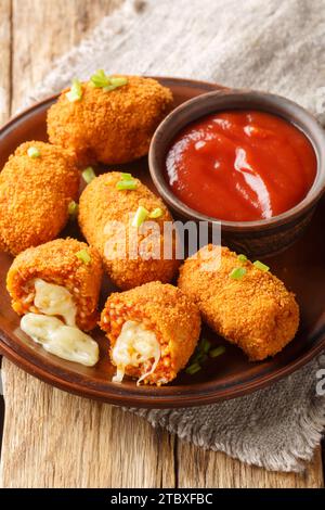 Suppli al telefono, fast food italiano, crocchette di riso al pomodoro fritte ripiene di mozzarella di primo piano sul piatto sul tavolo. Verticale Foto Stock