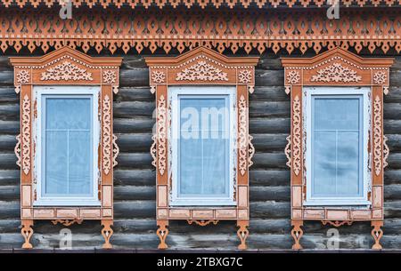 Tre finestre tradizionali con lastre di legno intagliato su muro di legno della casa mercantile residenziale del XIX secolo nel centro storico della città di Yelabuga, Foto Stock