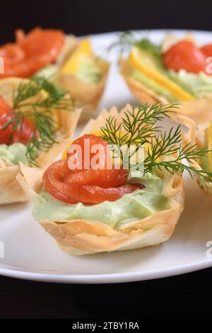 Avocado montato con crema di formaggio soffice nella mousse più delicata, una fetta di salmone e limone. Servita in cesti croccanti con pasta phyllo cotta al forno Foto Stock