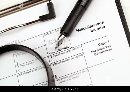 Modulo IRS 1099-misc reddito varie vuote su tablet A4 si trovano sul tavolo da ufficio con penna e lente di ingrandimento da vicino Foto Stock