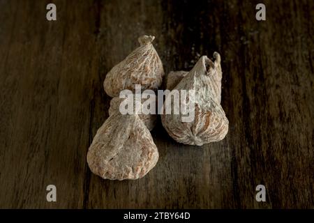 Fichi secchi pronti da mangiare dolci ricchi di minerali su tavola di legno con luce scura Foto Stock