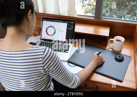 Donna che disegna grafici e grafici utilizzando tablet e notebook Foto Stock