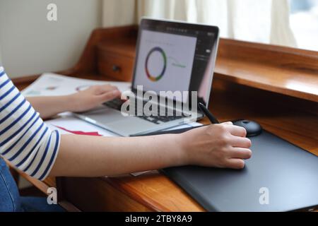 Donna che disegna grafici e grafici utilizzando tablet e notebook Foto Stock
