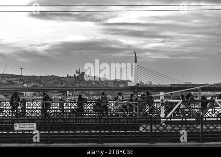 Istanbul, Turkiye - 22 novembre 2021: Gente che cammina e pesca sul ponte Galata che collega Karakoy a Eminonu attraverso il Corno d'Oro, Istanbul. Foto Stock