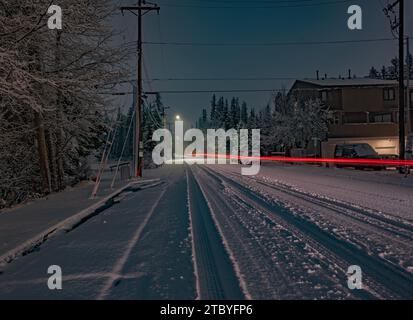 Vista notturna della neve che cade su una strada a Canmore, Alberta, Canada Foto Stock