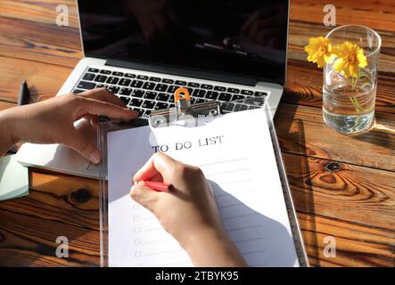 Un notebook bianco con un elenco di cose da fare scritto su di esso e un notebook Foto Stock