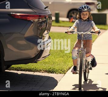 i bambini viaggiano in bicicletta a bordo di un'auto pericolosa. regole stradali pericolose per i bambini. Con prudente eccitazione. educazione alla sicurezza stradale. ciclista per bambini in bicicletta vicino Foto Stock