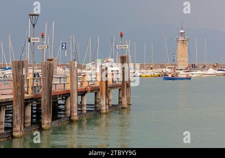 DESENZANO DEL GARDA, Italia - 26 agosto 2023: Marina sul lago di Garda, con un molo in primo piano e il faro sullo sfondo Foto Stock