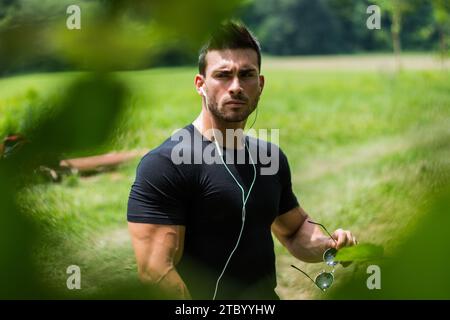 Un uomo con una camicia nera che regge un paio di cuffie Foto Stock
