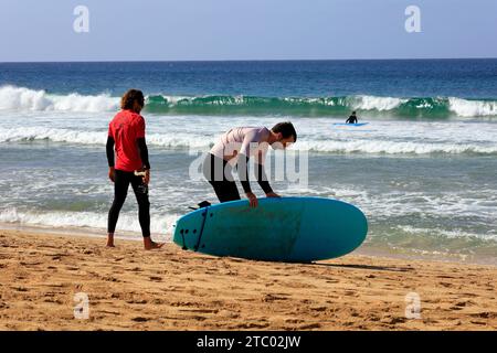 Uomo che prende la prima lezione di surf con istruttore individuale, El Cotillo, Fuerteventura, Isole Canarie, Spagna. Presa nel novembre 2023 Foto Stock