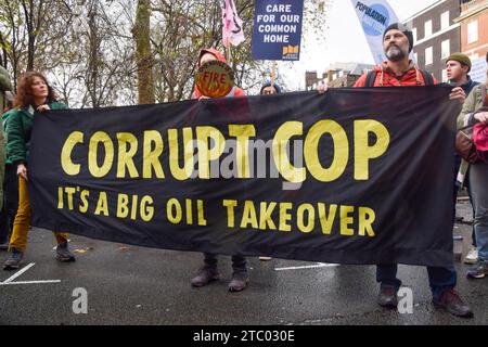 Londra, Regno Unito. 9 dicembre 2023. I manifestanti hanno uno striscione che dice "corrotto COP" durante la manifestazione. Gli attivisti del clima si sono riuniti fuori dalla sede centrale della BP nel centro di Londra per protestare contro le compagnie petrolifere che hanno preso il controllo della COP28 e invocato la giustizia climatica. Credito: SOPA Images Limited/Alamy Live News Foto Stock