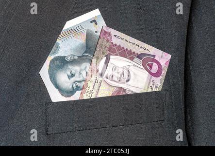 Banconota dell'Arabia Saudita con King Salman e banconota in yuan cinese con Mao Zedong in tasca per uomo d'affari. Foto del concetto di business dello scambio ra Foto Stock