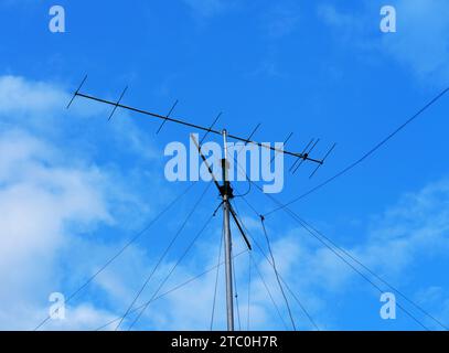 Un'antenna radio VHF con le corde di sostegno contro un cielo blu nuvoloso Foto Stock