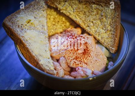 Cocktail di gamberi servito in una ciotola su tagliere di legno Foto Stock