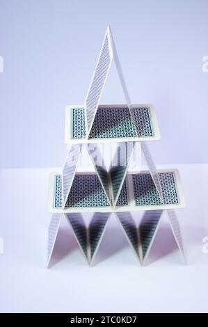 Gioco a piramide di carte in equilibrio, realizzato con carte da poker su sfondo bianco. Foto Stock