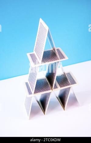 La piramide delle carte da gioco in equilibrio è realizzata con carte da poker su sfondo blu. Foto Stock