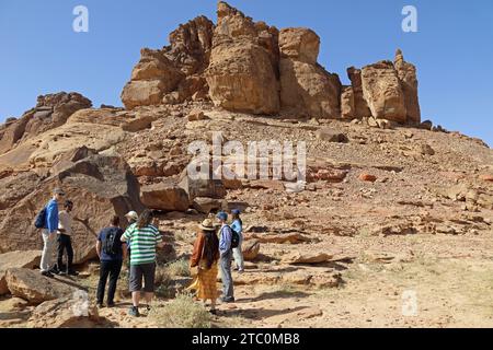 Turisti che trovano incisioni rupestri sul monte Umm Sinman nel grande deserto Narfoud dell'Arabia Saudita Foto Stock