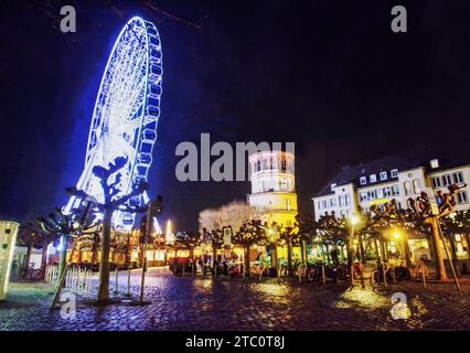 Stupore vista dell'ora blu sulla ruota panoramica e sulla piazza con alberi topiari (alberi di tiglio o polari?) In Dusseldorf illuminato di notte Foto Stock