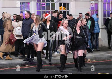 Broad Street, Birmingham 9 dicembre 2023 - i venditori hanno lottato per rimanere in posizione eretta sabato sera mentre raffiche di vento fino a 50 km/h colpivano Birmingham mentre Storm Elin colpiva la regione. I festaioli si sono rovinati i capelli, dato che gli edifici hanno creato un effetto tunnel del vento. La maggior parte indossava cappotti caldi e sciarpe, ma alcuni venivano fuori in abiti da festa, pronti a ballare tutta la notte, qualunque fosse il tempo all'aperto. I salti e i cappelli di Babbo Natale sono stati il tema della serata mentre la stagione delle feste di Natale è iniziata. Credito: Stop Press Media/Alamy Live News Foto Stock