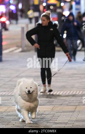 Broad Street, Birmingham 9 dicembre 2023 - i venditori hanno lottato per rimanere in posizione eretta sabato sera mentre raffiche di vento fino a 50 km/h colpivano Birmingham mentre Storm Elin colpiva la regione. I festaioli si sono rovinati i capelli, dato che gli edifici hanno creato un effetto tunnel del vento. La maggior parte indossava cappotti caldi e sciarpe, ma alcuni venivano fuori in abiti da festa, pronti a ballare tutta la notte, qualunque fosse il tempo all'aperto. I salti e i cappelli di Babbo Natale sono stati il tema della serata mentre la stagione delle feste di Natale è iniziata. Credito: Stop Press Media/Alamy Live News Foto Stock