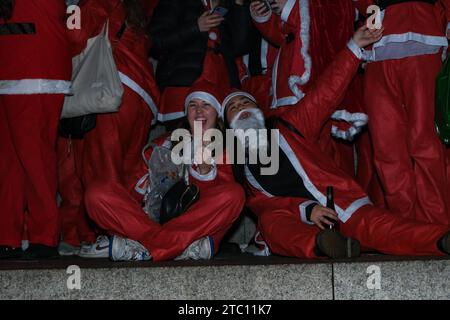 Londra, Regno Unito. 9 dicembre 2023. I festaioli del SantaCon vestiti con abiti Babbo Natale e altri costumi festivi arrivano a Trafalgar Square, dove hanno posato per le foto di gruppo alla base della colonna di Nelson. L'evento annuale, che vede i partecipanti prendere parte a un giro dei pub, è organizzato anche in altre città del mondo. Credito: Fotografia dell'undicesima ora/Alamy Live News Foto Stock