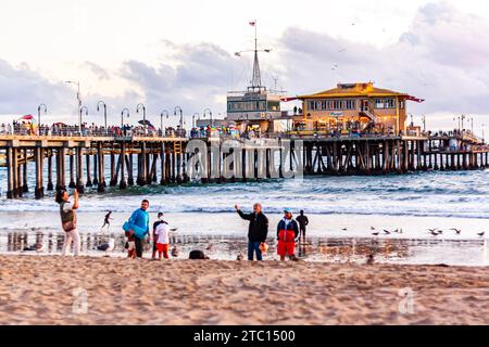 Turisti che scattano foto sulla spiaggia di Santa Monica, con il molo di Santa Monica sullo sfondo, pomeriggio d'estate nel sud della California Foto Stock