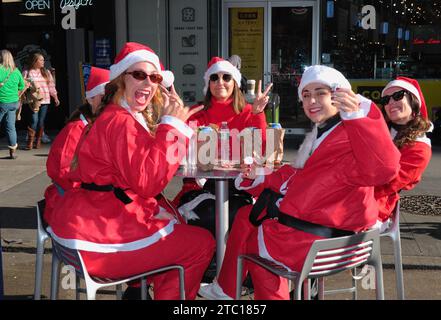 New York, Stati Uniti. 9 dicembre 2023. I partecipanti al SantaCon che indossano costumi di Babbo Natale siedono a un tavolo. I festaioli vestiti da Babbo Natale o altri personaggi natalizi si sono riuniti a Manhattan, New York City per il SantaCon, un giro annuale di bar a tema natalizio che raccoglie fondi per beneficenza. I donatori hanno ricevuto l'ingresso nei locali partecipanti, come bar e club. Credito: SOPA Images Limited/Alamy Live News Foto Stock